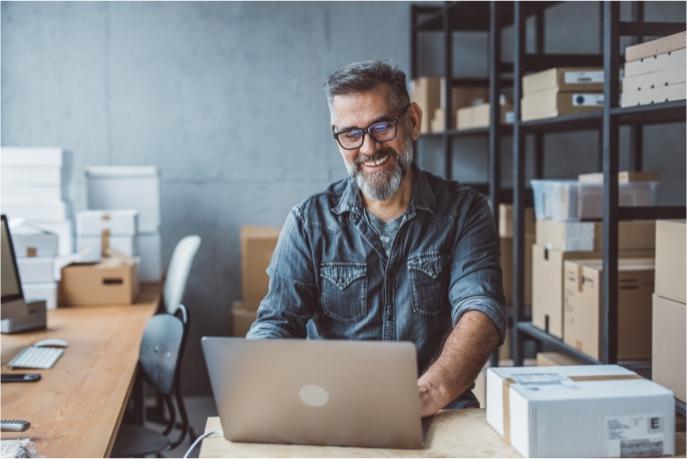 Merchant on a laptop preparing to ship a package.